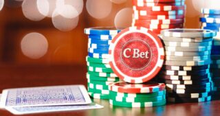 Bunte Stapel von Pokerchips und zwei verdeckte Spielkarten auf einem Tisch mit warmem Licht im Hintergrund symbolisieren eine Continuation Bet.