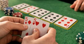 Ein Spieler hält zwei Fünfen in der Hand, während offene Gemeinschaftskarten auf dem grünen Pokertisch liegen und die Situation Counterfeit beim Poker zeigen.