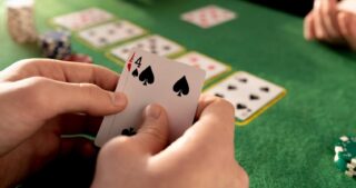 Ein Spieler hält eine Pik-Vier in der Hand, während mehrere offene Karten auf dem grünen Pokertisch liegen und die Szene einen Draw beim Poker darstellt.