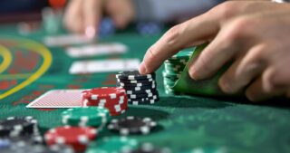 Eine Hand schiebt Pokerchips über den grünen Spieltisch, während die Szene eine String Bet beim Poker darstellt.