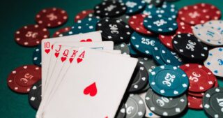 Eine starke Herzhand mit Zehn, Bube, Dame, König und Ass liegt zwischen vielen Pokerchips auf grünem Filz und symbolisiert Value beim Poker.
