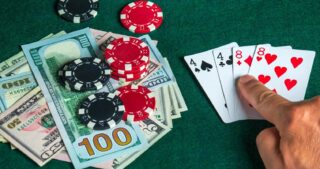 Mit Online Poker Geld verdienen: Spielgeld, Pokerchips und Pokerkarten auf einem grünen Tisch.
